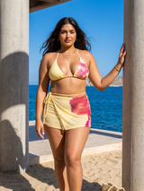Woman in a colorful bikini standing by a concrete structure with water in the background
