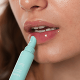 Person applying a light pink lip color with a turquoise lip liner pencil.