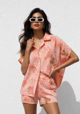 Woman wearing a pink floral outfit against a white background
