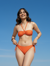 Woman wearing an orange bikini against a clear blue sky