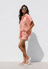 Woman wearing a pink floral outfit against a white background
