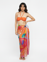 Woman wearing an orange bikini top and colorful sarong on a white background