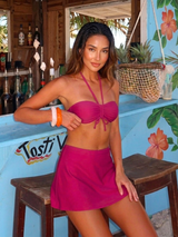 Woman in a pink bikini standing in front of a bar with tropical decor