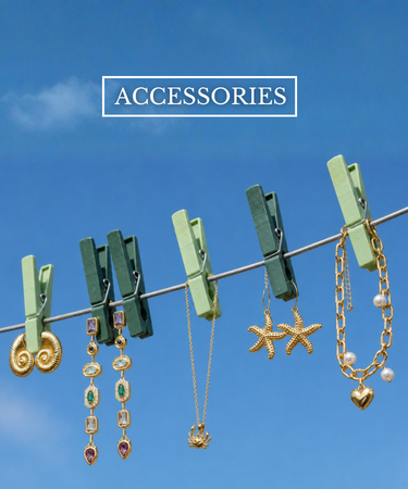 A collection of gold-toned jewelry clips and necklaces hanging from a clothesline with green wooden clothespins against a bright blue sky. The text 'ACCESSORIES' is displayed at the top.