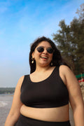 Curvy woman wearing sunglasses and a black round neck top