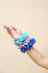 Hand wearing a blue scrunchie with pink and white pattern