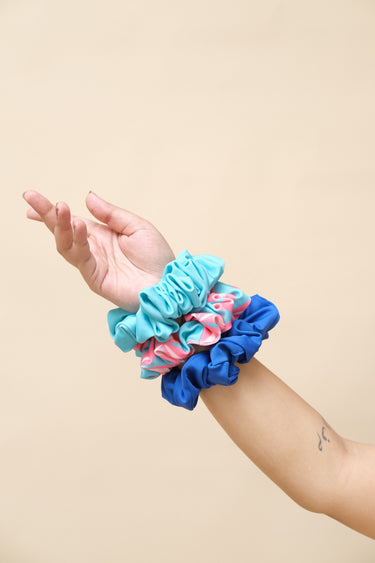 Hand wearing a blue scrunchie with pink and white pattern