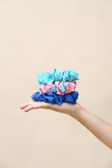 Hand holding three colorful scrunchies