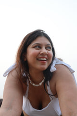 Woman wearing a white top and pearl necklace