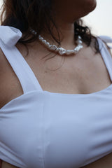 Woman wearing a white top and pearl necklace