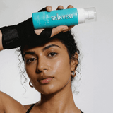 Woman holding a Skinvest skincare product against a white background