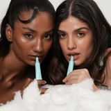 Two women holding blue applicators over white foam