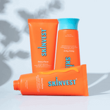 Three orange skincare products with blue text on a light gray background