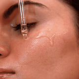 Close-up of a dropper with liquid being applied to the skin.