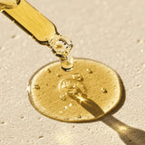 Gold dropper with liquid on a beige background