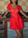 Woman wearing a bright red dress with floral patterns in a kitchen setting