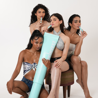 Three women sitting together with a large light blue tube-like object on a white background