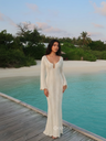 Woman in a white dress standing by a pool with greenery in the background