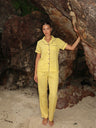 Woman in yellow checkered pajama set standing in a cave-like setting.