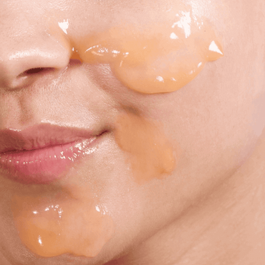 Close-up of a person applying a skincare product to their face.