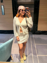 Woman taking a mirror selfie wearing a light-colored outfit with a headscarf.