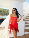 Woman in a red dress standing on a yacht deck with a scenic background