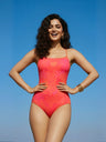 Woman wearing a bright pink swimsuit against a clear blue sky
