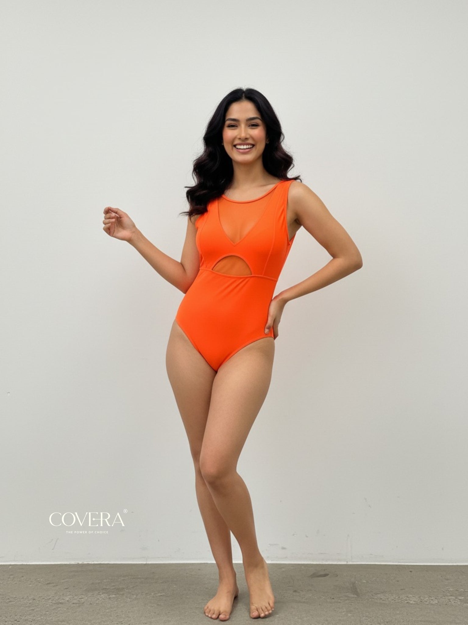 Woman wearing an orange swimsuit with a plain background, featuring the brand 'COVERA'.