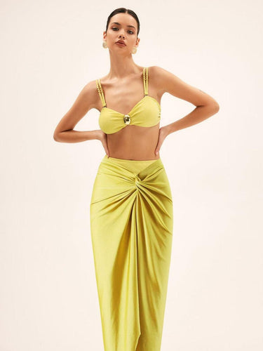 Woman wearing a yellow bikini top and skirt on a beige background