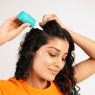 Person applying a product to their hair with a bottle labeled 'suave'