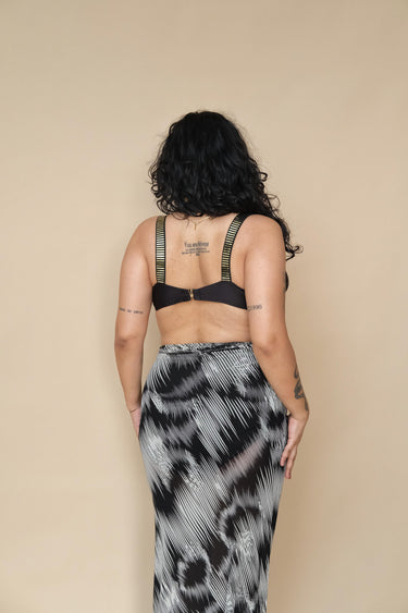 Plus size woman wearing a black bikini top and patterned skirt 