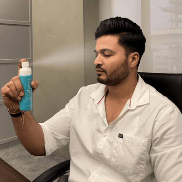 Man holding a blue bottle labeled 'Salutest' in an office setting