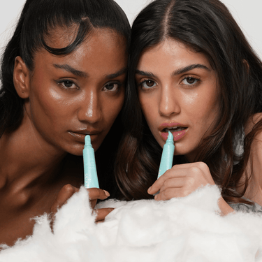 Two women holding blue applicators over white foam
