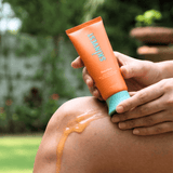 Person applying sunscreen to their shoulder with a Skynipel tube.
