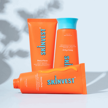 Three orange skincare products with blue text on a light gray background