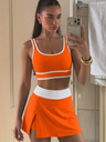 Woman taking a mirror selfie wearing an orange and white swim skort outfit.