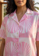 Person wearing a pink and white shell patterned shirt.